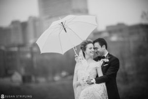 A destination wedding photographer captures a beautiful moment of a bride and groom embracing under an umbrella.