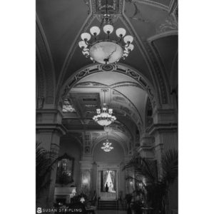 A black and white photo of a chandelier in an ornate building captured by a talented destination wedding photographer.
