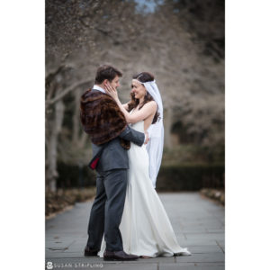 A bride and groom hugging at their winter wedding in the Brooklyn Botanic Garden.
