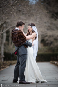 A bride and groom embrace in front of a tree during their winter wedding at the Brooklyn Botanic Garden.