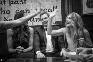 A black and white photo of a group of people high fiving each other at a rainy day wedding at Capitale.