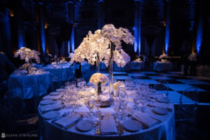 A rainy day wedding reception at Capitale adorned with white orchids and illuminated by blue lighting.