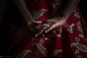 An Indian bride's hand holding a wedding ring.