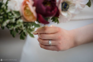 A summer bride holding her wedding ring and flowers during an elopement at Brooklyn Bridge Park.