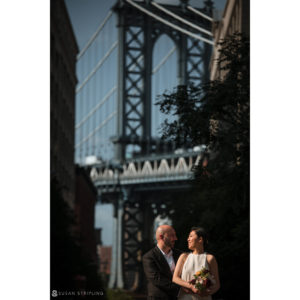 Summer elopement of bride and groom at Brooklyn Bridge Park with the iconic Manhattan Bridge in the backdrop.