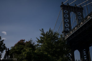 A summer elopement at the Brooklyn Bridge Park with the Manhattan Bridge standing tall under a blue sky.