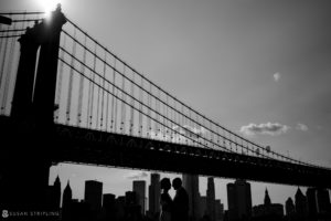 Keywords inserted: Black and white photo of a couple kissing under the Brooklyn Bridge during their summer elopement at Brooklyn Bridge Park.