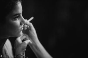 A black and white photo of a woman smoking a cigarette at a summer wedding.