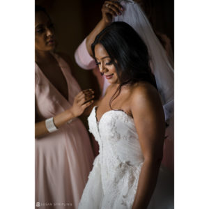An Indian bride is gracefully putting on her exquisite wedding dress at the luxurious Tarrytown House Estate.