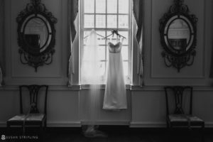 A black and white photo of a wedding dress hanging in a window at Union Trust in Philadelphia.