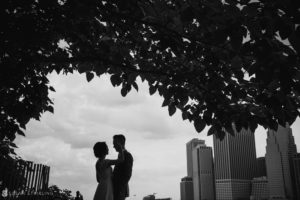 A black and white photo of a bride and groom standing under a tree at their wedding.