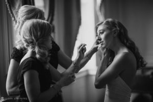 A bride getting her makeup done at a wedding at Union Trust in Philadelphia, captured in a black and white photo.