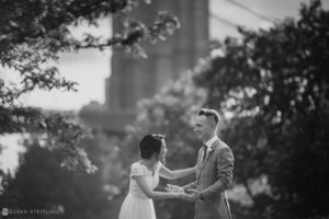Black and white photo of a bride and groom in front of the Brooklyn Bridge on their wedding day at 26 Bridge.