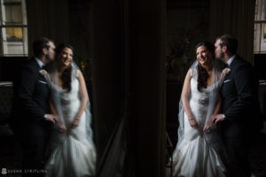 A bride and groom standing in front of a mirror at their wedding.