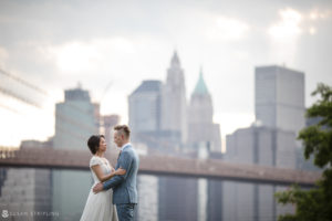 A bride and groom celebrating their wedding in front of the Brooklyn Bridge.