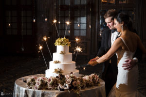 A bride and groom cutting their wedding cake with sparklers at the Crystal Tea Room.