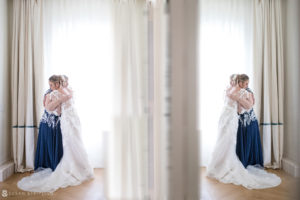 A bride and her bridesmaid standing in front of a window at their wedding at the Bridgehampton Tennis and Surf Club.
