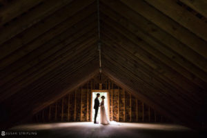 A wedding at the Bridgehampton Tennis and Surf Club, with a bride and groom standing in an attic.