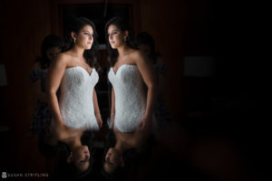 A bride at Pier Sixty, dressed in a wedding gown, admiring her reflection in the mirror.