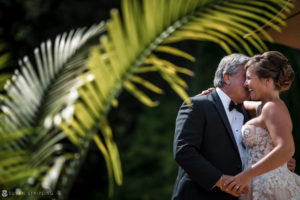 A bride and groom hugging in front of a palm tree at their wedding at the Berkeley Oceanfront Hotel.
