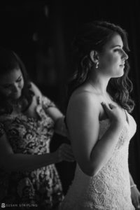 A bride putting on her wedding dress in a black and white photo at Pier Sixty.