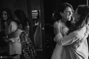 Two brides hugging each other in front of a mirror at their wedding at Pier Sixty.