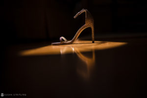 A high heeled shoe sitting on a wooden floor at a wedding venue.