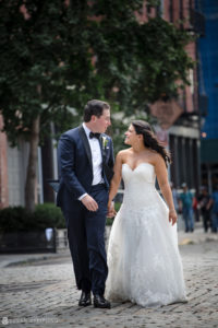A bride and groom having a wedding at Pier Sixty, walking down a cobblestone street.