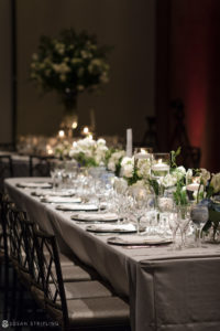 A beautiful long table set with white flowers and candles, creating a romantic ambiance for a wedding at Pier Sixty.
