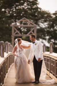 A bride and groom standing on a wooden bridge during their wedding at the Berkeley Oceanfront Hotel.