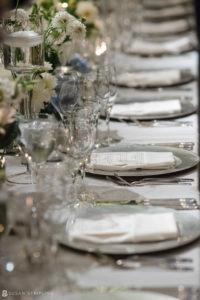 A long table set with white plates and silverware at a wedding at Pier Sixty.