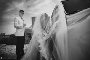 A bride and groom standing next to a car at their wedding at the Berkeley Oceanfront Hotel.