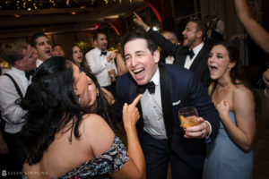A man in a tuxedo dances with other people at a wedding reception at Pier Sixty.