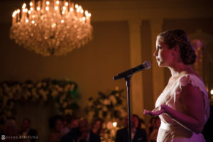 A bride singing into a microphone at a wedding reception at the Berkeley Oceanfront Hotel.