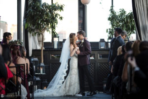 A summer wedding at the Gramercy Park Hotel where a bride and groom share a heartfelt kiss during their ceremony.