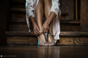 A woman tying her shoes on a riverside farm staircase.