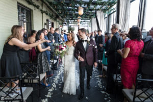 A bride and groom walk down the aisle at a summer wedding ceremony.