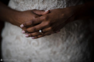 A close up of a bride's hands holding a wedding ring at a summer wedding.