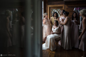 A bride and her bridesmaids are posing in front of a mirror at Riverside Farm, during their summer wedding.