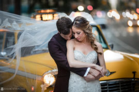 A bride and groom hugging in front of a taxi cab after their summer wedding at Gramercy Park Hotel.