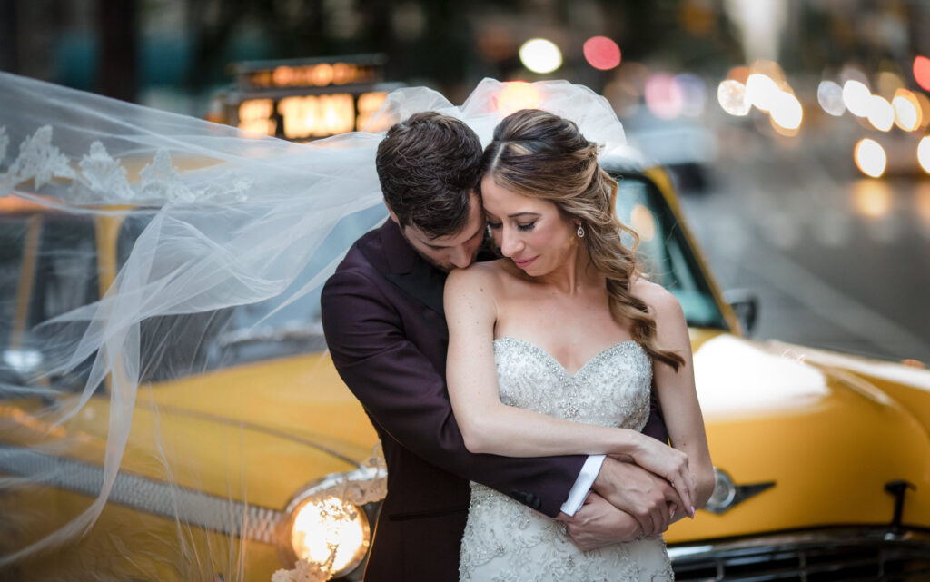 A bride and groom hugging in front of a taxi cab after their summer wedding at Gramercy Park Hotel.