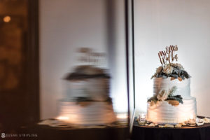 A summer wedding cake sitting on a table in front of a mirror at the Gramercy Park Hotel.