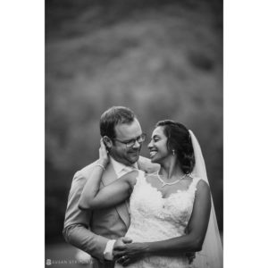 A bride and groom embracing in front of a mountain at their summer wedding at Riverside Farm.