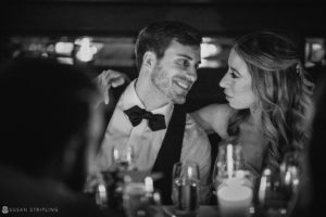 A bride and groom smiling at each other during their summer wedding in a dimly lit room at the Gramercy Park Hotel.
