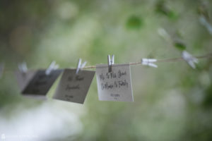 Wedding etiquette cards hanging on a clothes line at a summer wedding.