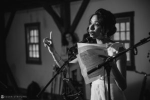 A woman singing into a microphone at a summer wedding.