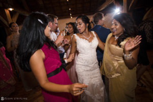 A group of women dancing at a Riverside Farm wedding reception during the summer.