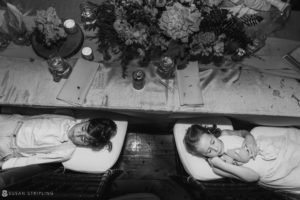 Two children laying down on a table at Riverside Farm in black and white.