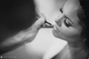 A bride getting her makeup done in a black and white wedding photo in New York.