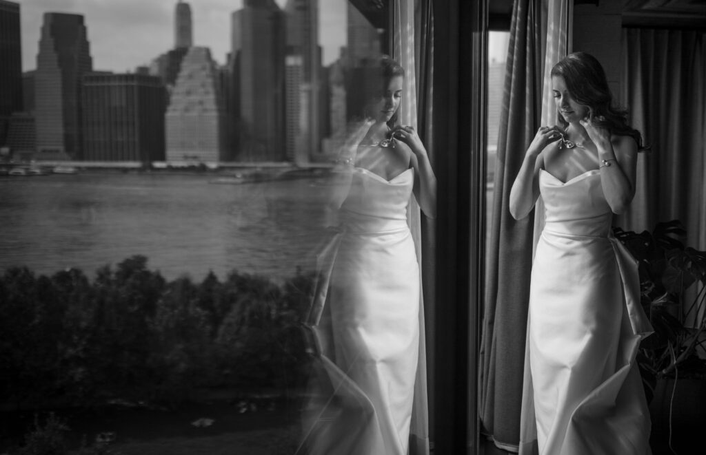 A bride is standing in front of a window with a view of the city at Hotel Brooklyn Bridge.